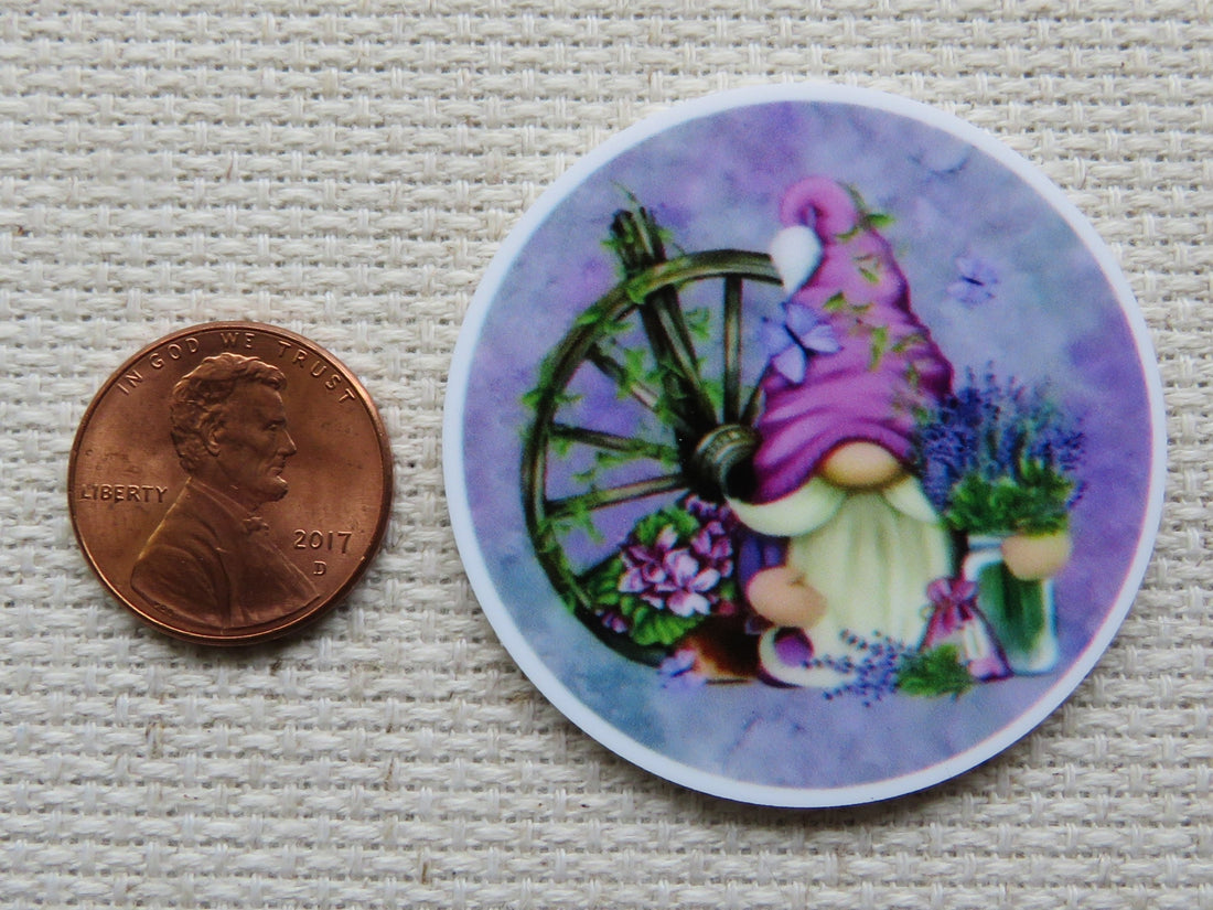 First view of Pinkish purple gnome in a purple circle with a wagon wheel and a vase of lavender flowers minder.